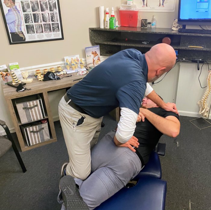 Chiropractic treatment session applying a spinal adjustment to a patient