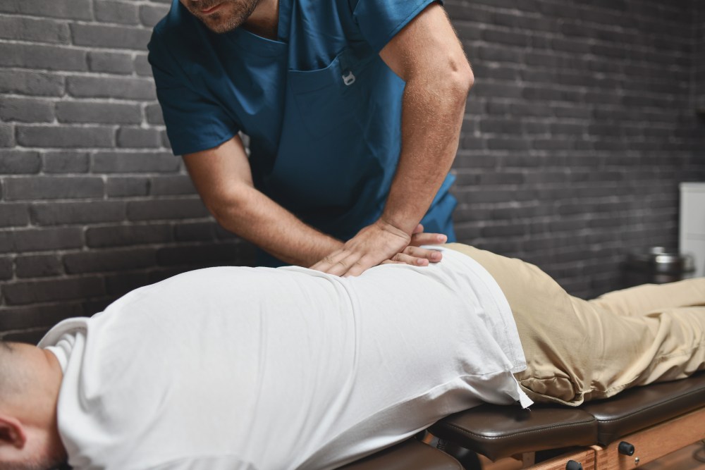 Healthcare professional performing a manual spinal adjustment on a patient lying face down