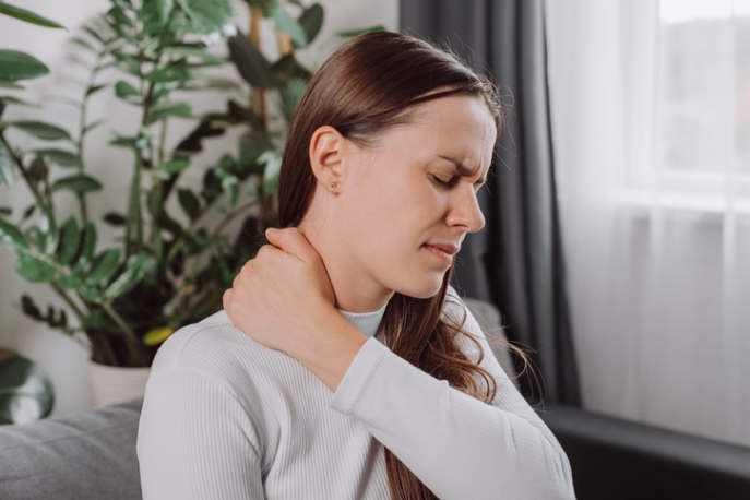 Person holding the side of the neck, indicating neck pain or discomfort